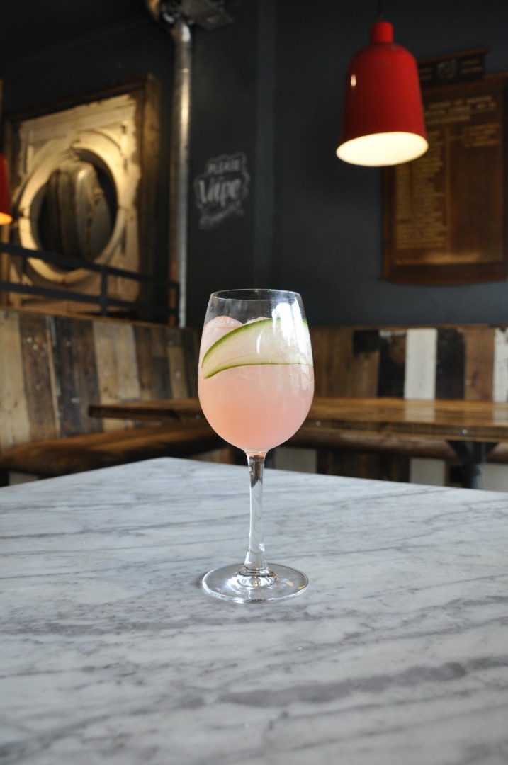 An image of a light pink drink called a Kiss, standing on a table in the Dancing Moose in Poole. A green leaf sits decoratively within the glass